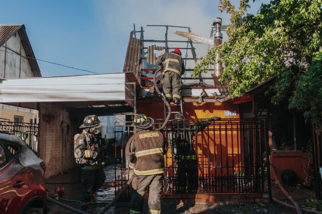 Firefighters working at a house with smoke rising from the roof