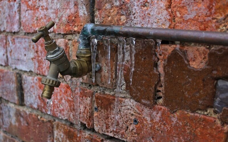 Frozen pipe covered in icicles during a hard winter freeze.