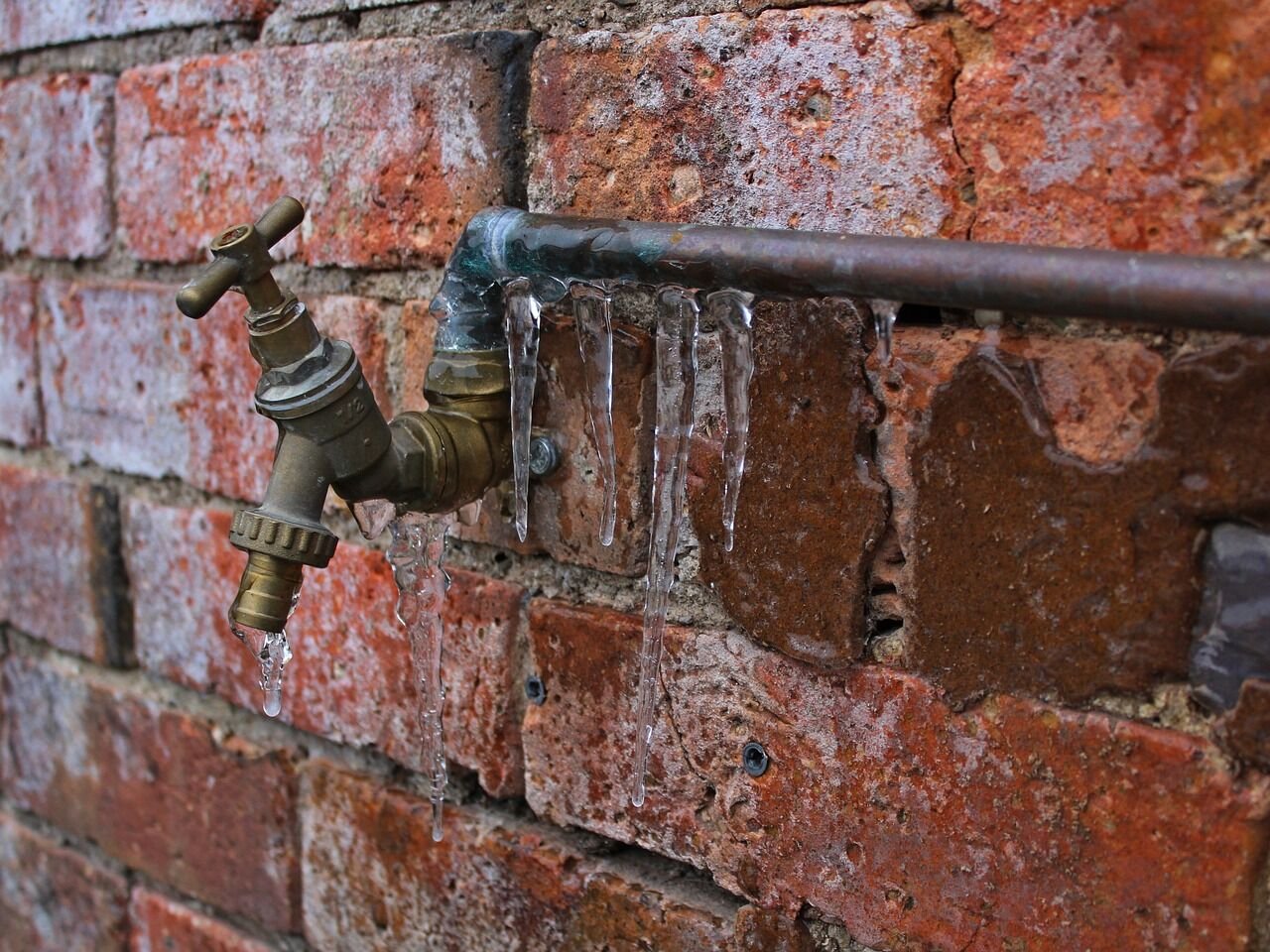 Frozen pipe with icicles hanging from it after a hard freeze