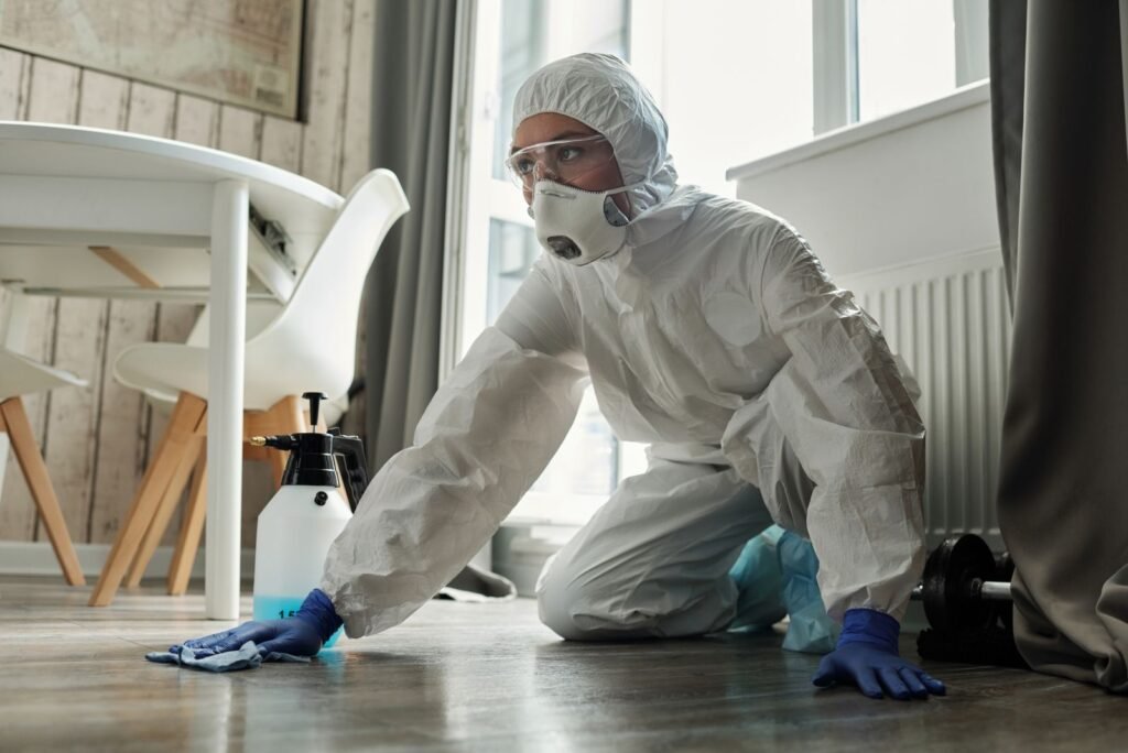 Worker in protective suit and respirator removing mold
