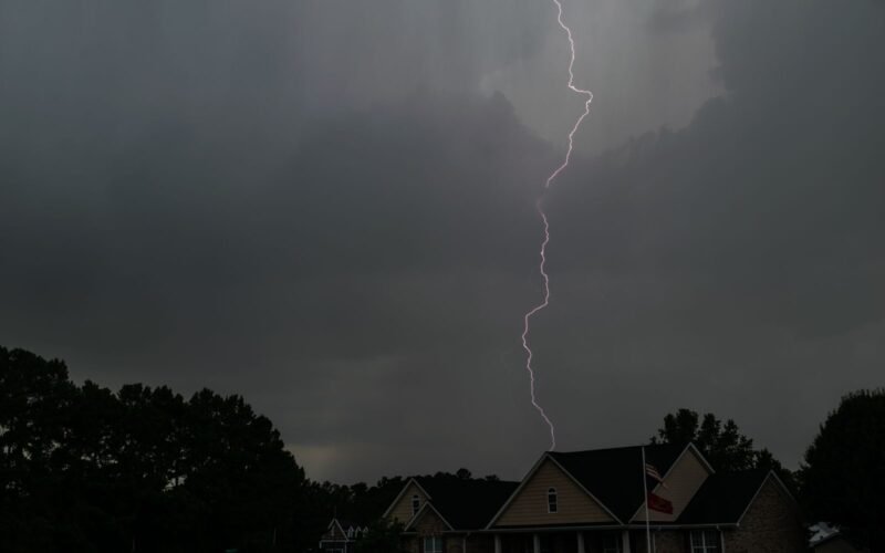 Lightning bolt striking over suburban houses during a thunderstorm.